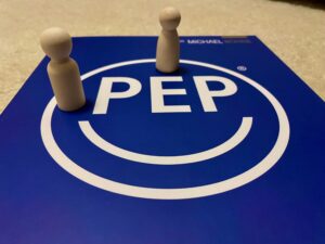 Coaching mit PEP B Holzfiguren auf einem PEP-Zeichen als Symbol für Coaching mit PEP